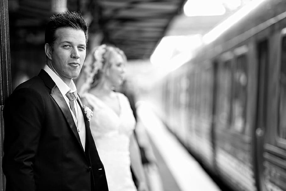 grayscale photography of standing man beside his bride near train HD wallpaper
