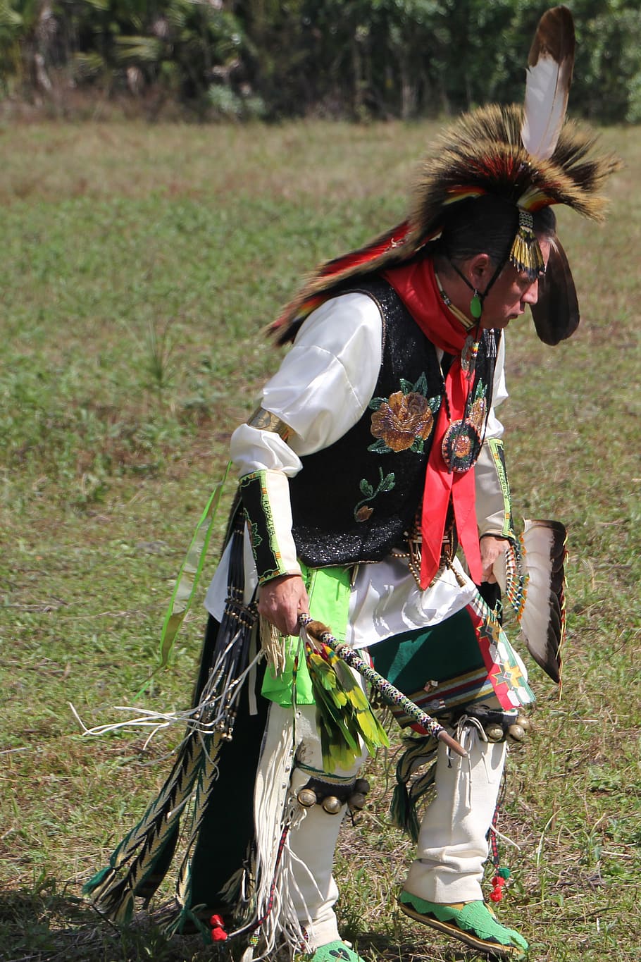 man standing on grass pavement, native american, dancer, costume