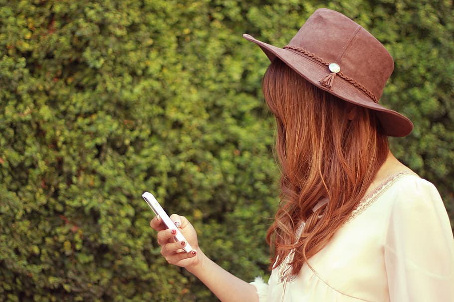 close up photo of person wearing brown hat and white shirt holding smartphone, HD wallpaper