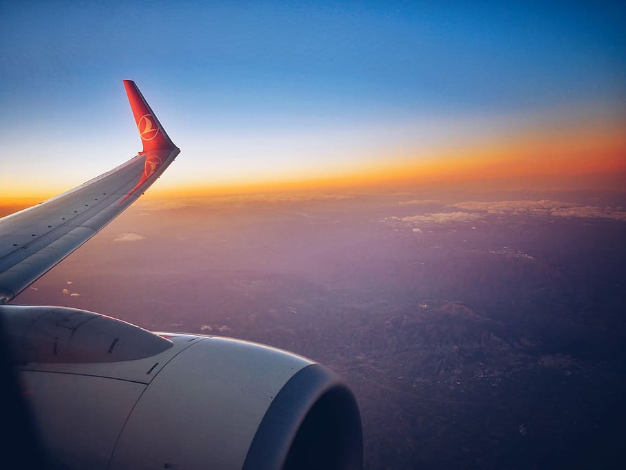 photograph white and red airplane wing, white and red Lufthansa airplane with the view of left wing during golden hour