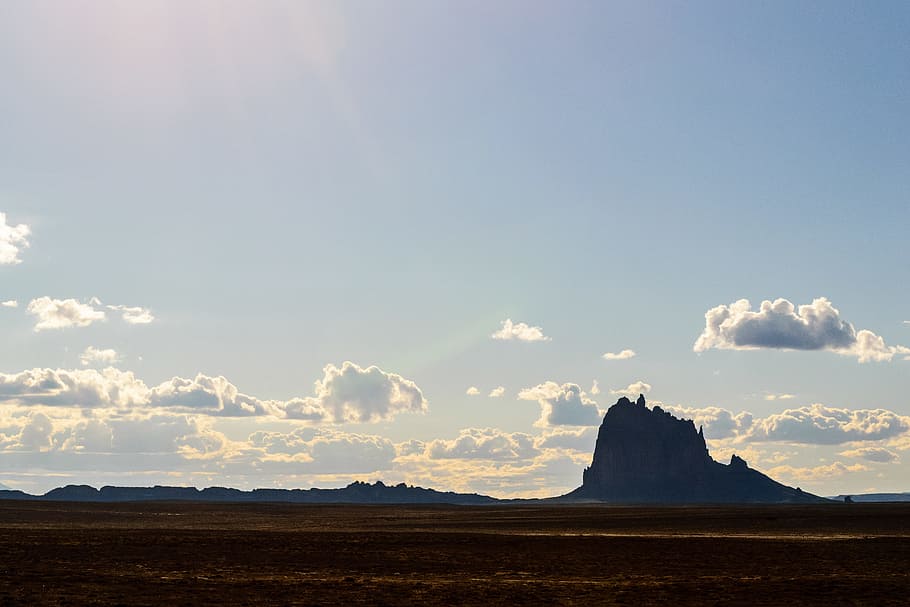 grey stone formation under blue sky, silhouette of mountains between sky and sand at daytime HD wallpaper