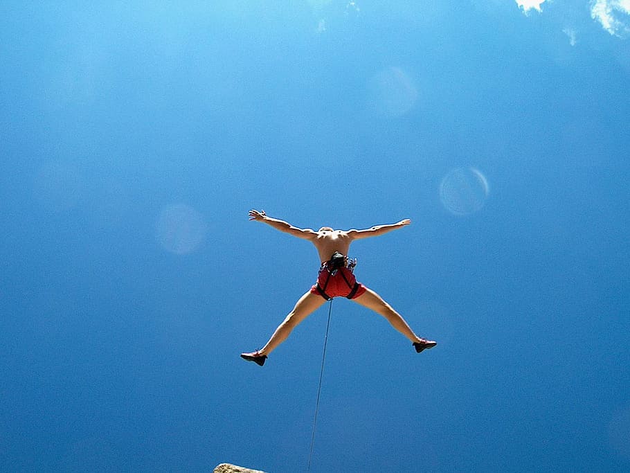 man wearing red shorts with black harness while bungee jumping