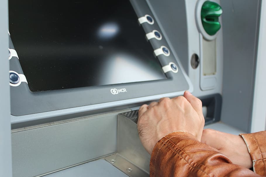 person's hands near gray machine, atm, pin, number field, withdraw cash