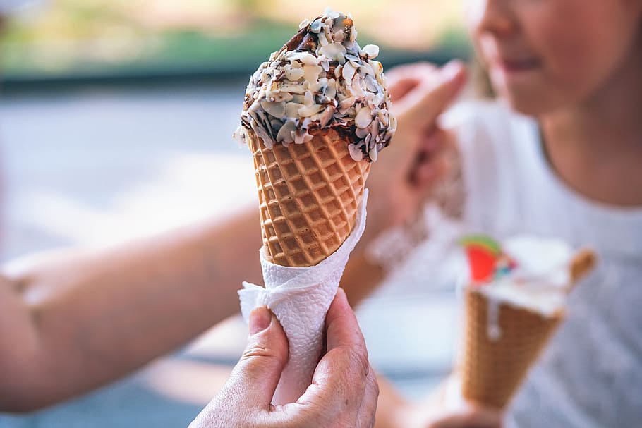 person holding ice cream in cone, selective focus photography of sugar cone with chocolate ice cream and peanuts on top, HD wallpaper