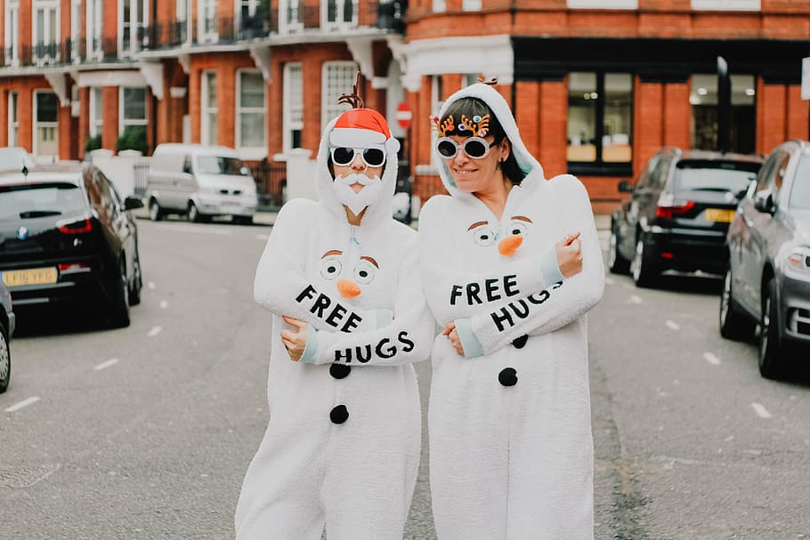 two people in snowman costumes standing on street, hug, woman