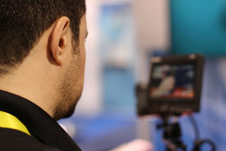man wearing black collared shirt near flat screen monitor, television
