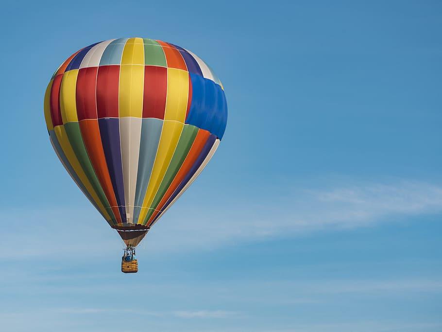 panning photography of flying blue, yellow, and red hot air balloon, focus photography of hot-air balloon