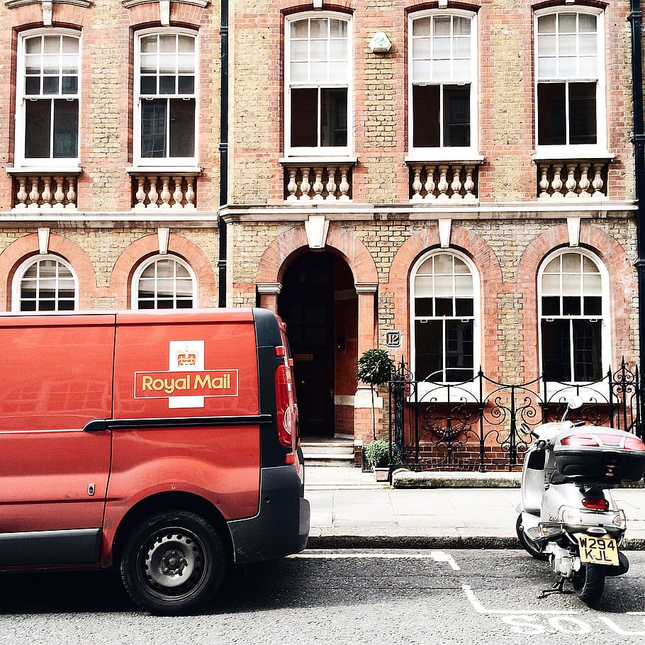Red Royal Mail Parked Near Brown Brick Building, architecture