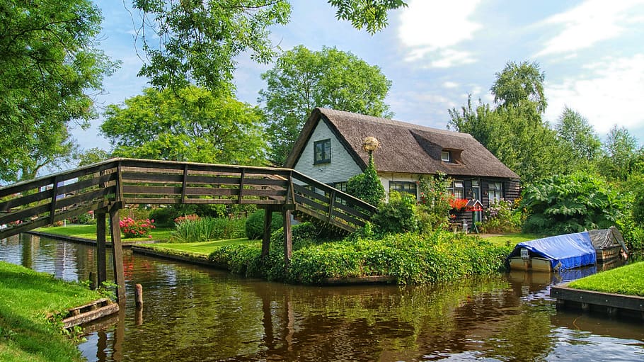 landscape photography of brown house near brown bridge across body of water at daytime