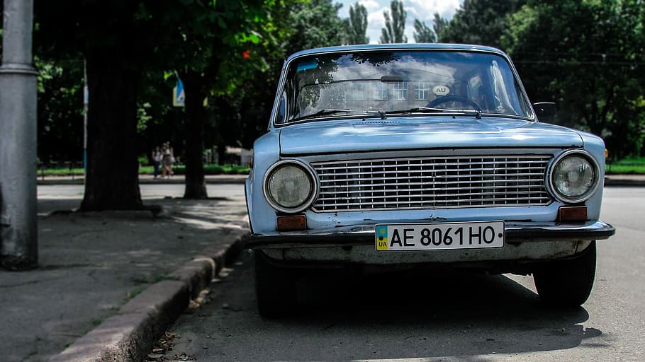 blue car parked near grey street light post under the shade of a tree during daytime HD wallpaper