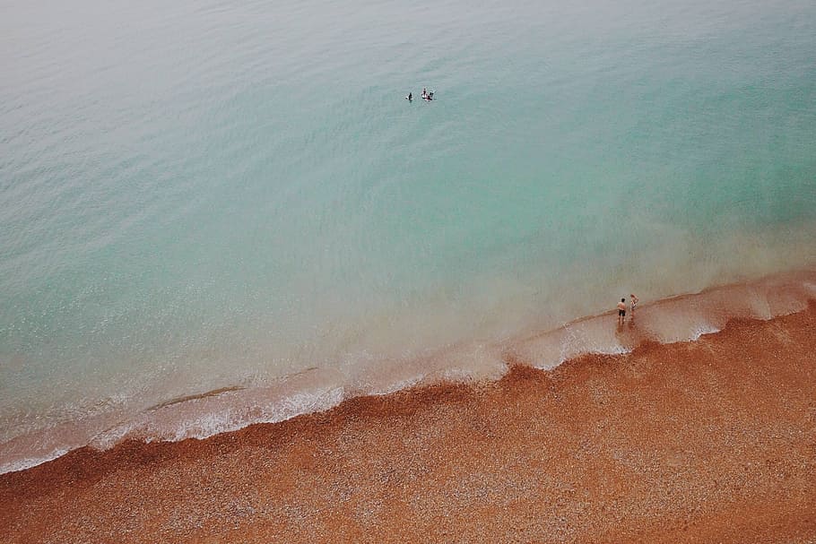aerial view of people at seashore, aerial photo of two person standing on seashore during daytime HD wallpaper