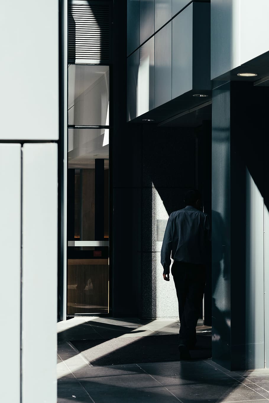 man walking on gray tiled pathway inside building, man walking inside a room HD wallpaper
