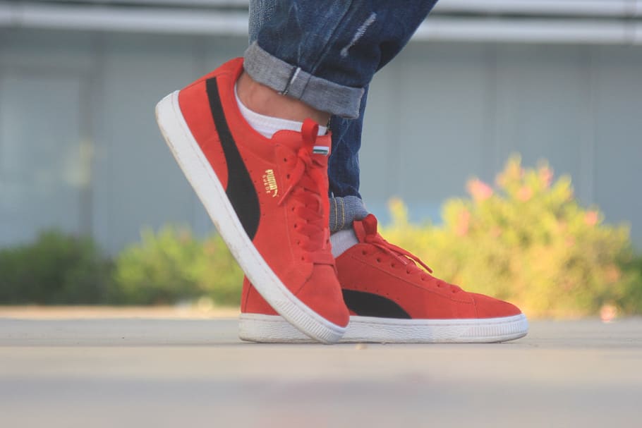 person wearing pair of red Puma shoes 