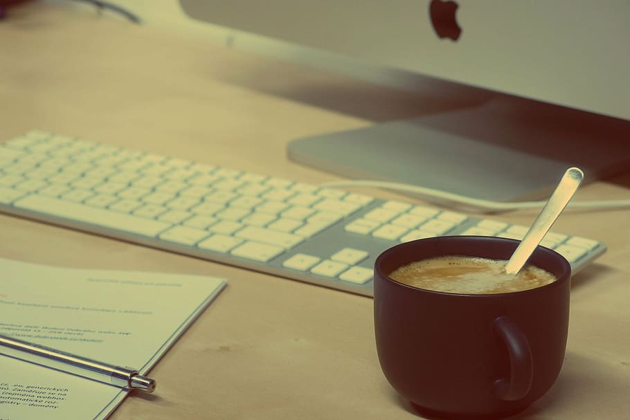 black filled cup beside white Apple keyboard on brown surface HD wallpaper