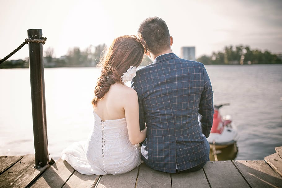 couple siting on sea dock in front of a personal watercraft HD wallpaper
