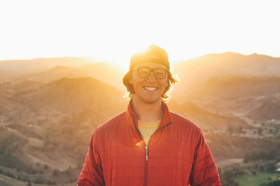 Man in glasses with smile standing in the sunlit mountains HD wallpaper