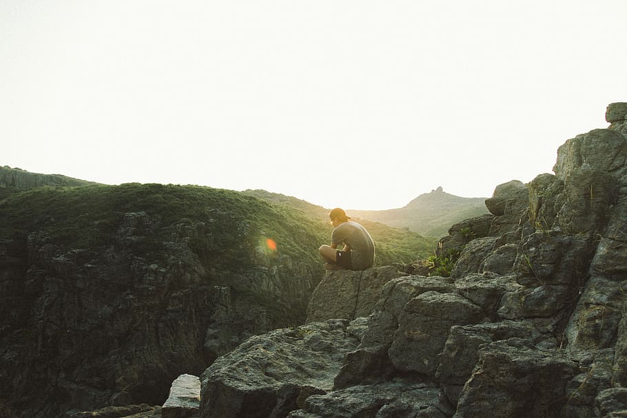 man sitting near cliff during sunrise, person sitting on rock at edge of mountain HD wallpaper