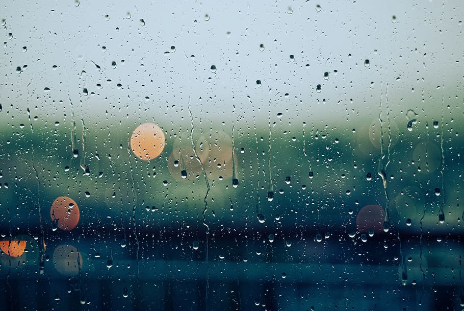 view of bokeh lights from behind a glass with water droplets running down HD wallpaper