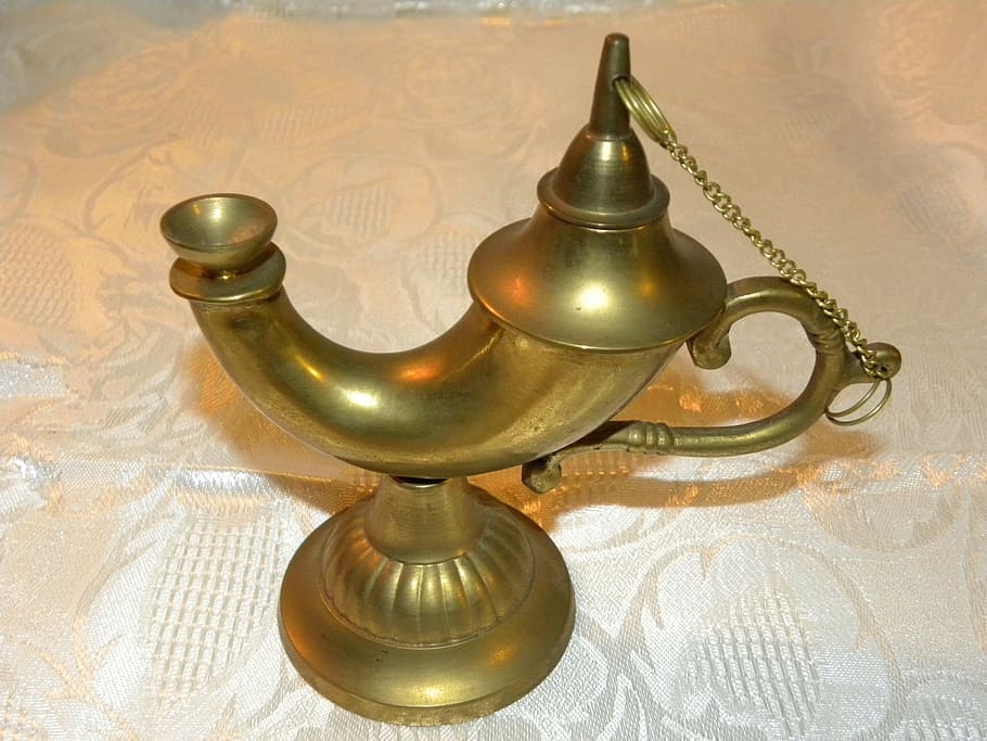 brass-colored footed oil lamp on white fabric textile, genie lamp
