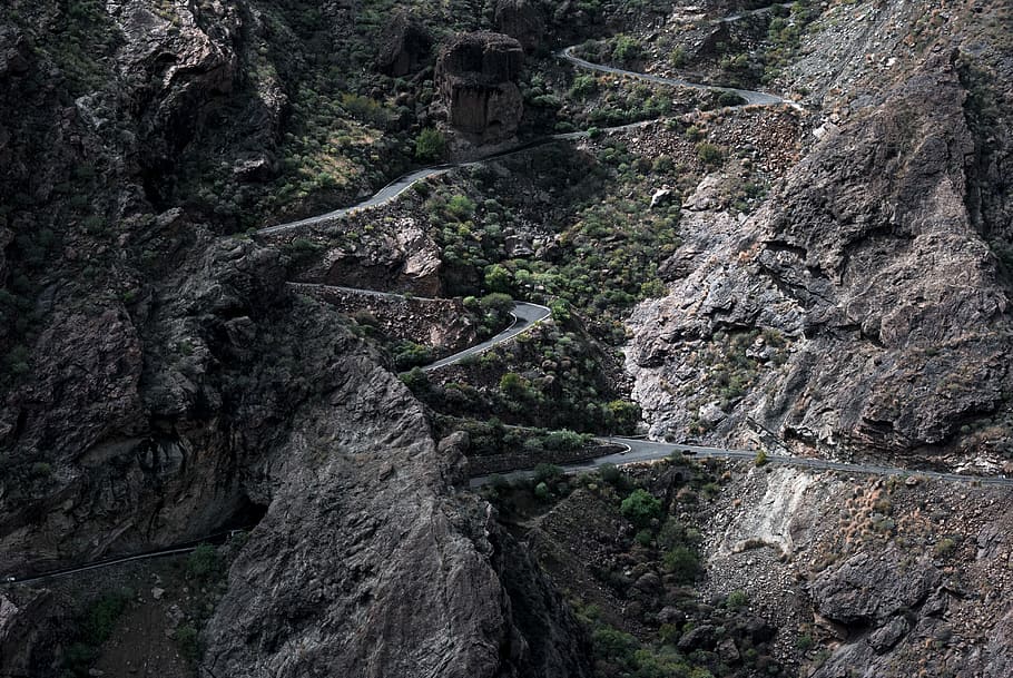 aerial photography of mountain pass, gray concrete road surrounded with trees at daytime HD wallpaper