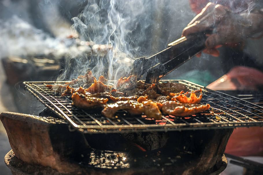 selective focus photography of person grilling meat, smoke, bbq