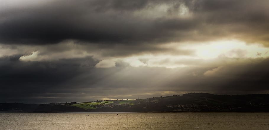 landscape photography of body of water near mountain during crepuscular rays HD wallpaper