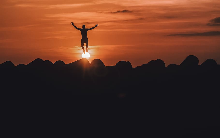 silhouette of man jumping during golden hour, mountain, cloud