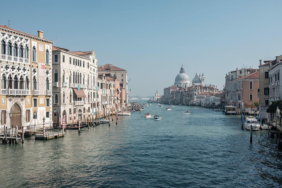 boats running on sea between buildings, white and beige concrete buildings near body of water HD wallpaper