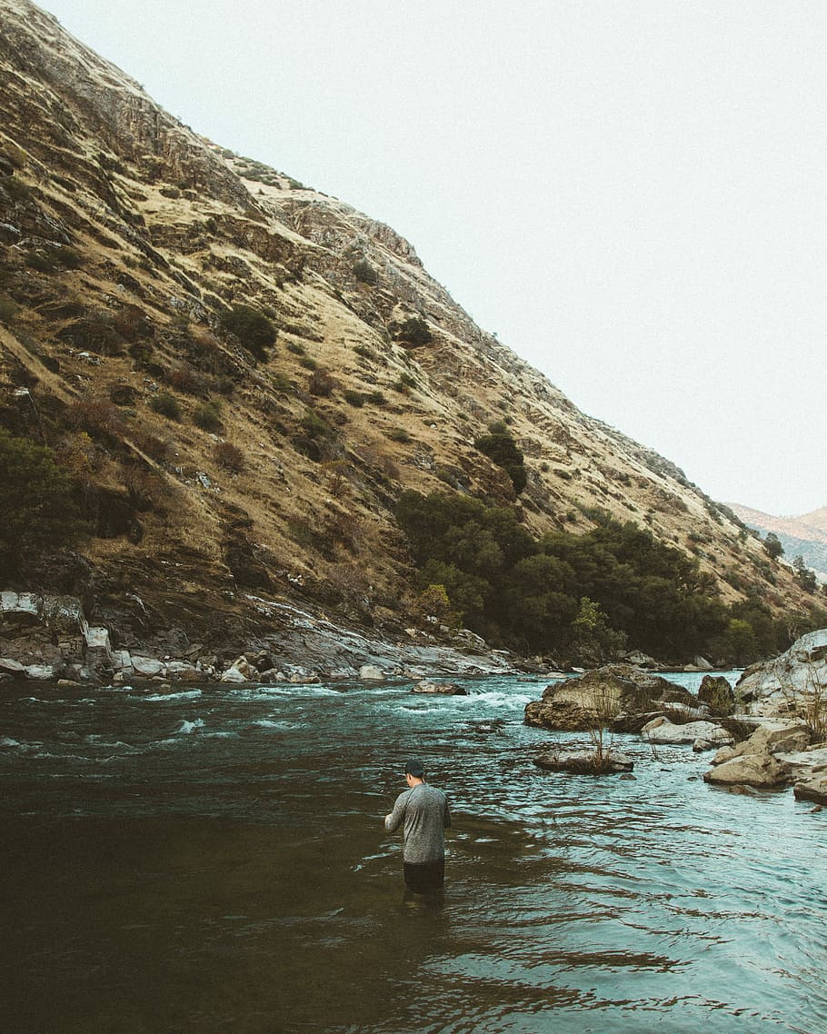 man in water near hill, photography of person surrounded by body of water near mountain during daytime HD wallpaper
