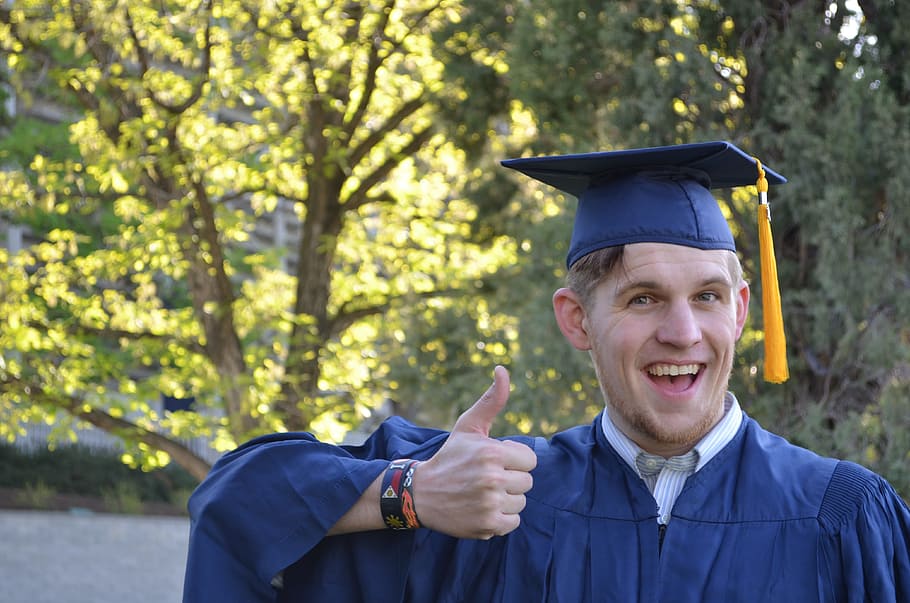 man in mortarboard and academic dress showing thumbs up sign