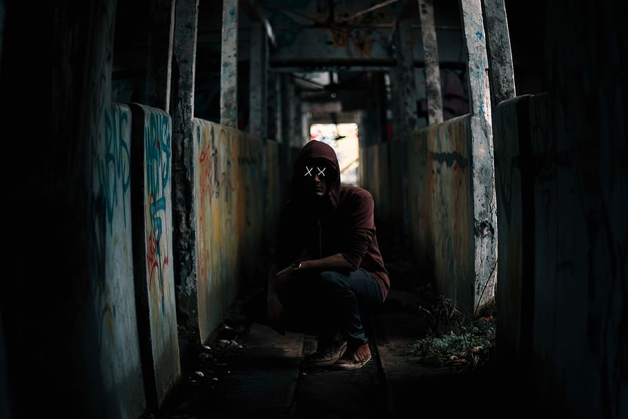 sitting man on abandoned building during daytime, x-eyed man wearing red hoodie sitting between walls with vandalism, HD wallpaper