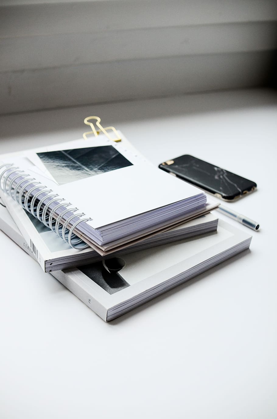 white spiral notebook beside black smartphone on white table, black and white iPhone marble case near ballpoint pen and three books, HD wallpaper