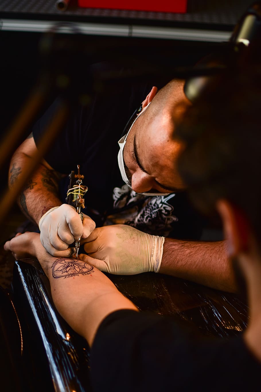 man doing tattoo on human arm, man tattooing person on his left arm