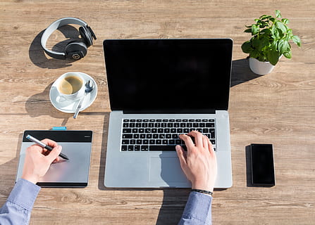 person using MacBook Pro and trackpad on top of brown wooden table HD wallpaper
