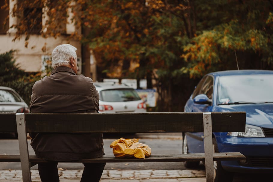 man sitting on bench, man wearing brown jacket sitting on bench looking at car, HD wallpaper