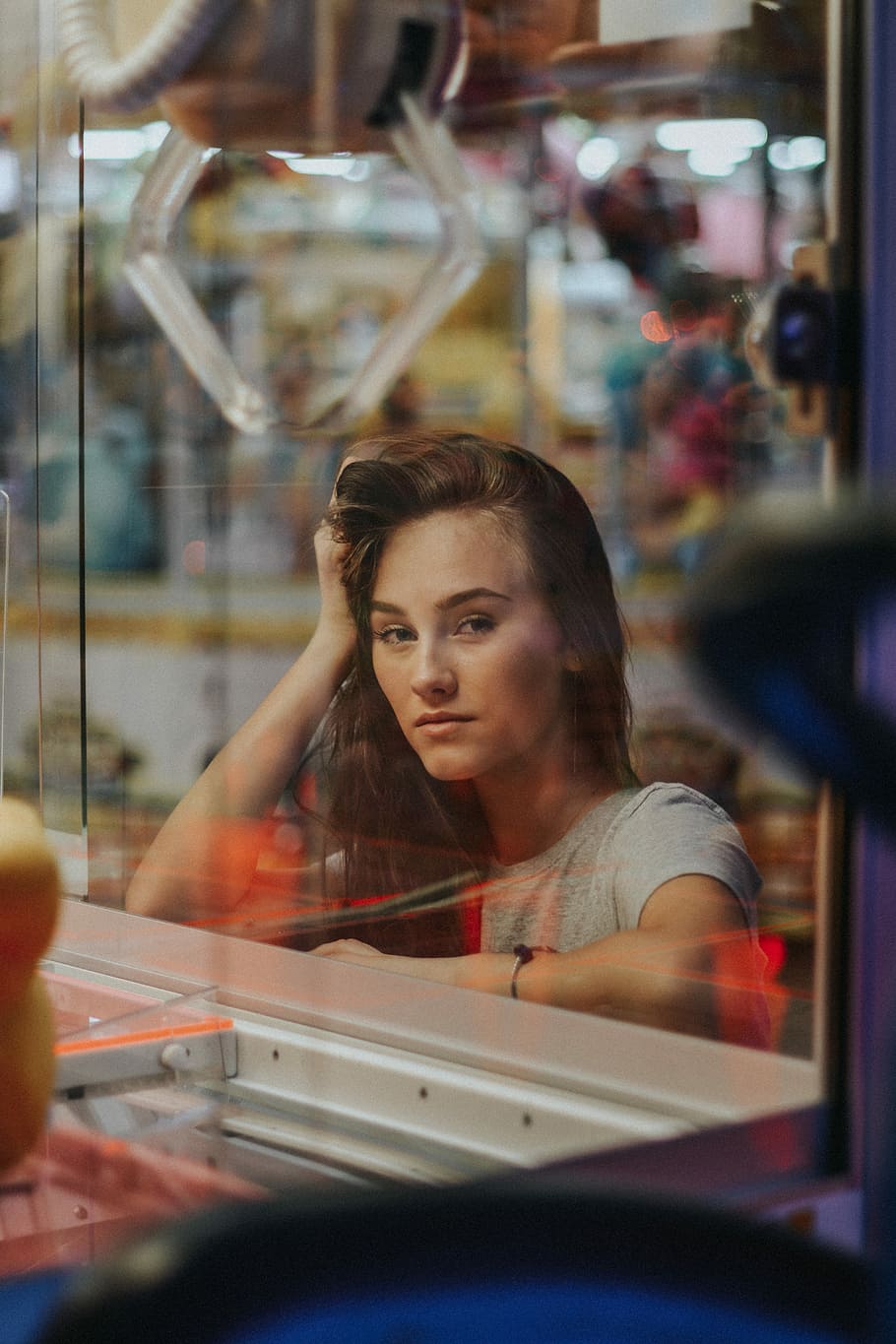 woman posing near arm arcade machine, woman in gray shirt standing in glass wall HD wallpaper