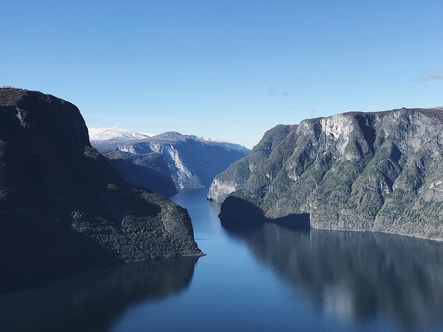 calm body of water between mountains under blue sky during daytime, landscape photography of body of water HD wallpaper