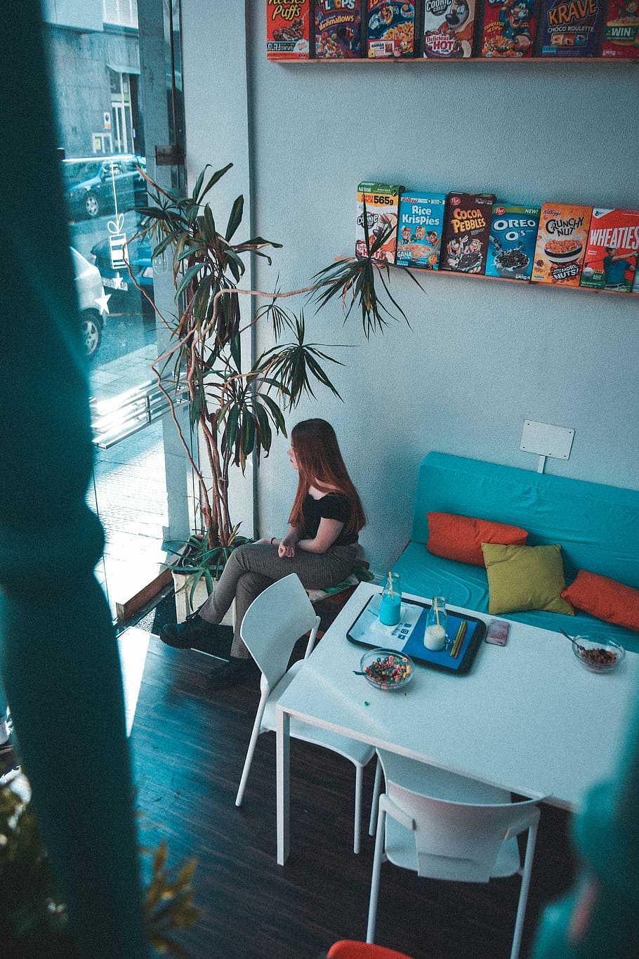 woman sitting near table under shelves with boxes, woman sitting beside blue couch HD wallpaper