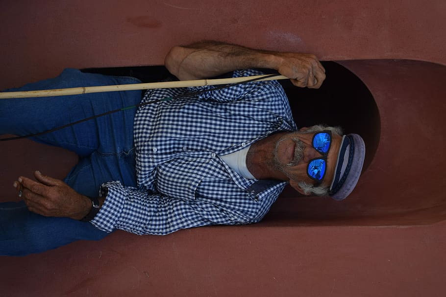 man with sunglasses sitting, man sitting on brown surface while holding stick HD wallpaper