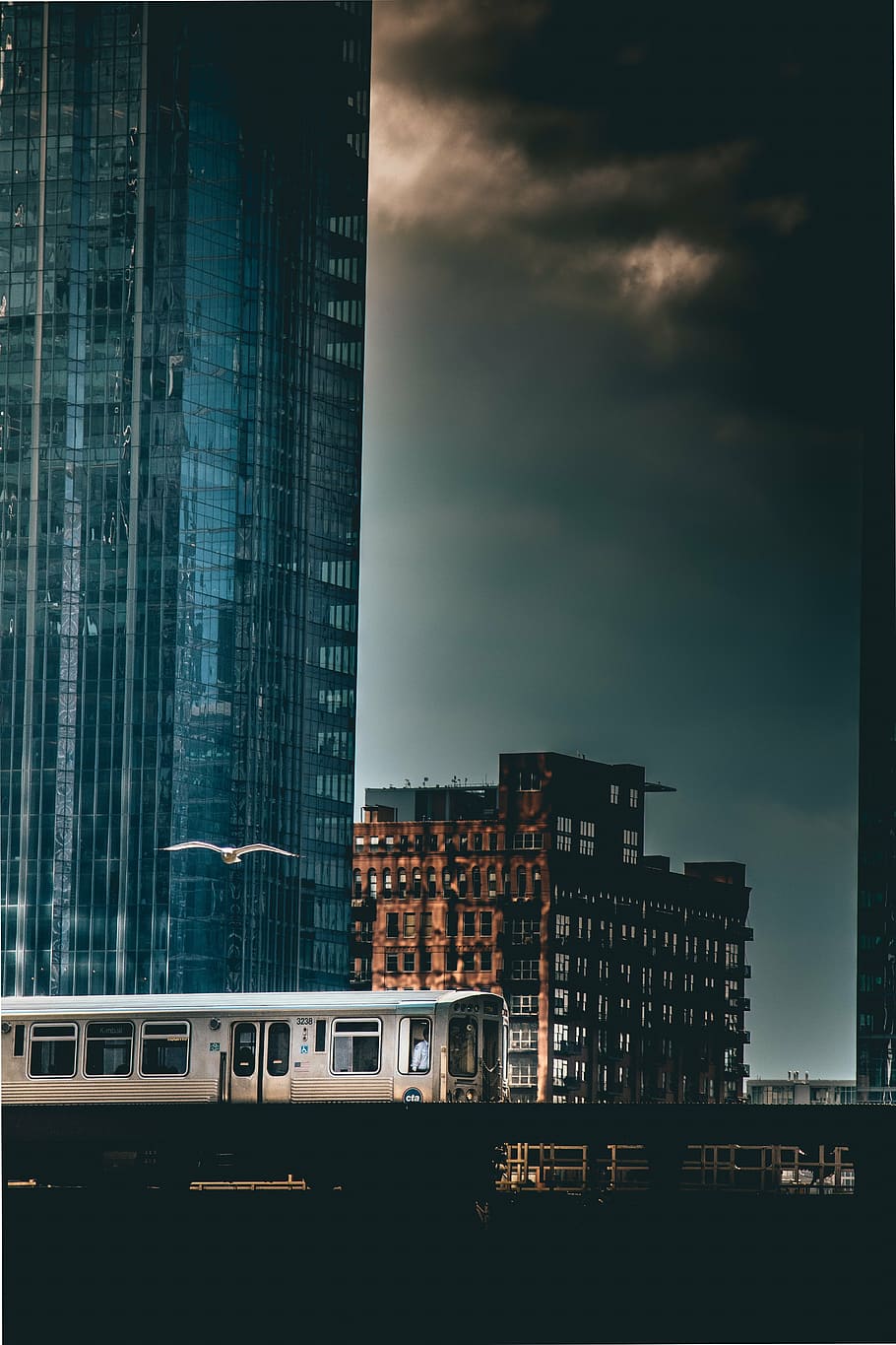 gray bus beside blue glass building under thick black clouds HD wallpaper