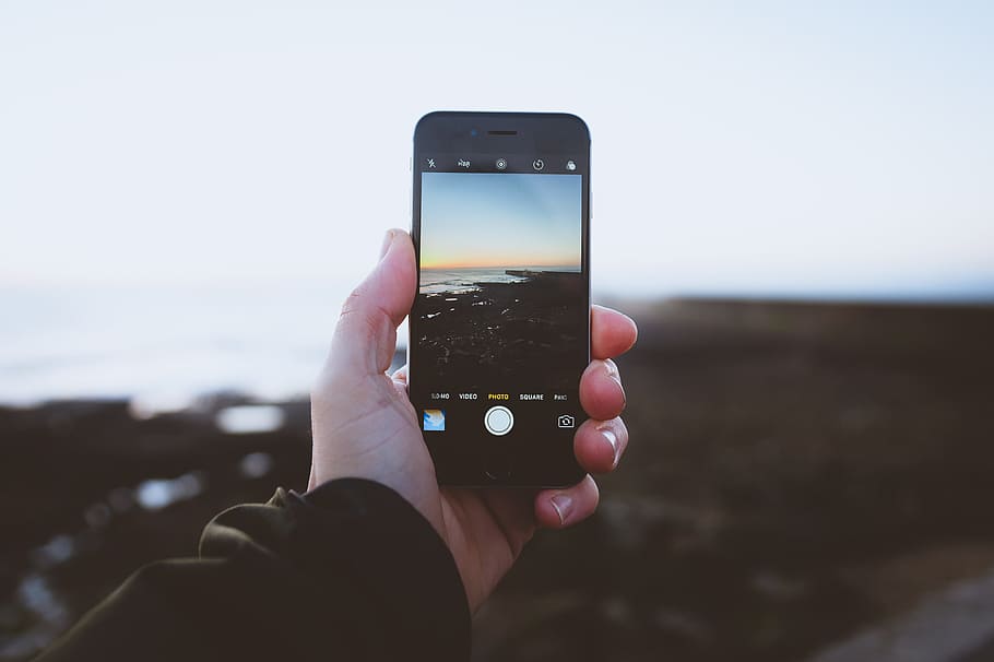 person taking photo of landscapes using iPhone during daytime, person taking photo of sea during golden hour HD wallpaper