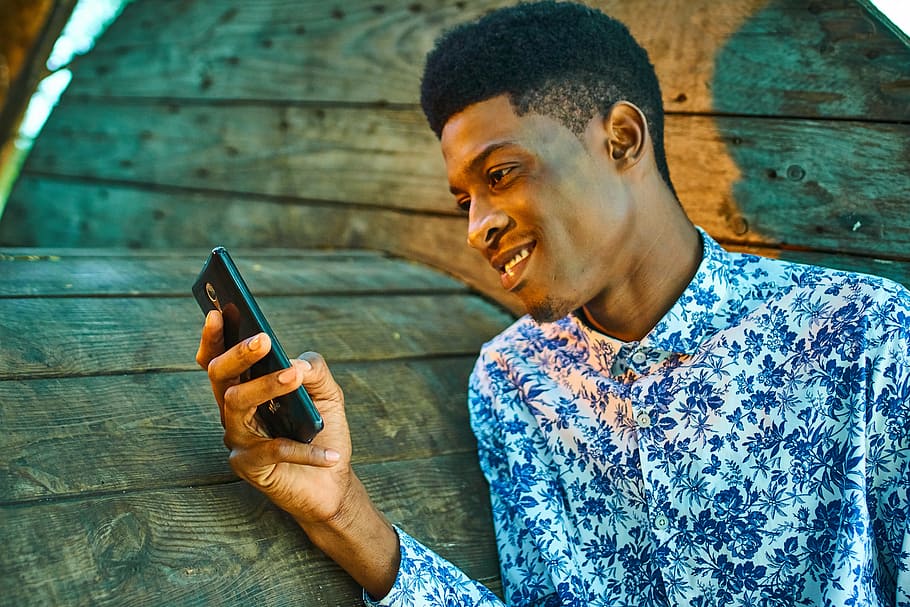 man wearing white and blue dress shirt holding black smartphone HD wallpaper
