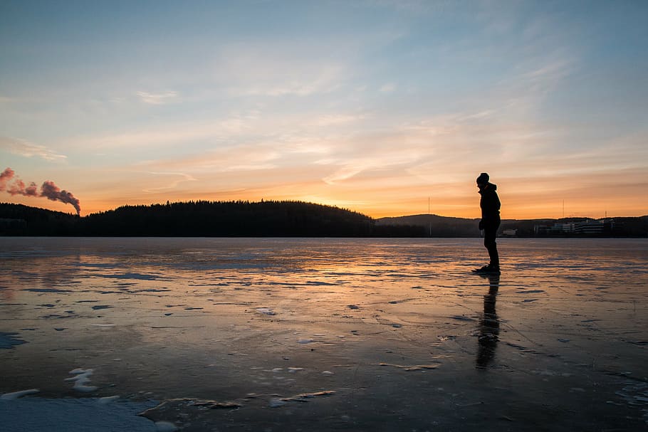 silhouette photo of person standing near body of water during sunset HD wallpaper