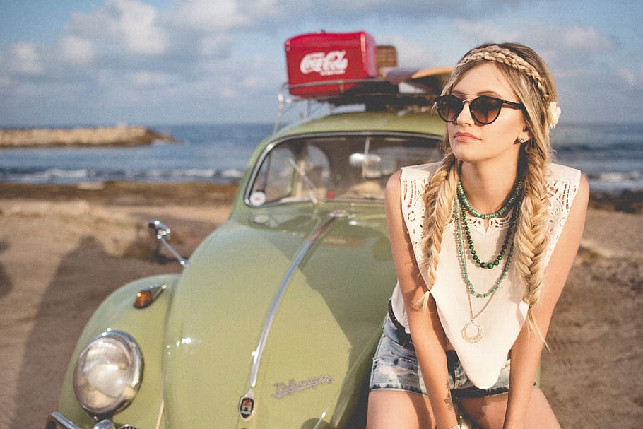 woman sitting in front of green Volkswagen Beetle on beach sand during daytime HD wallpaper