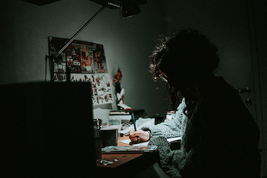 low light photography of woman in gray knit sweatshirt writing on desk, silhouette photo of person writing on desk with study lamp HD wallpaper