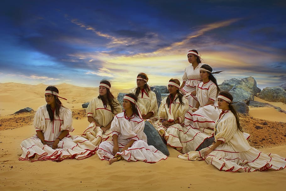 group of women wearing white dress sitting on brown sand, raramuris