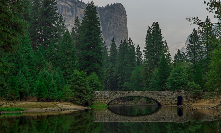 reflection of concrete bridge on river with mountain view, landscape photography of bridge surrounded with pine trees HD wallpaper