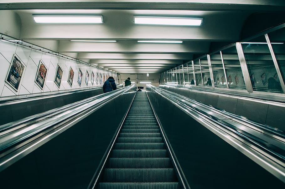 empty escalator beside two people standing beside railings inside room with lights turned on HD wallpaper