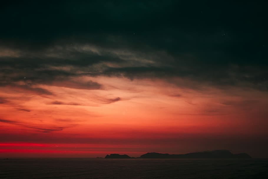 body of water near island, silhouette of mountain under orange sky HD wallpaper