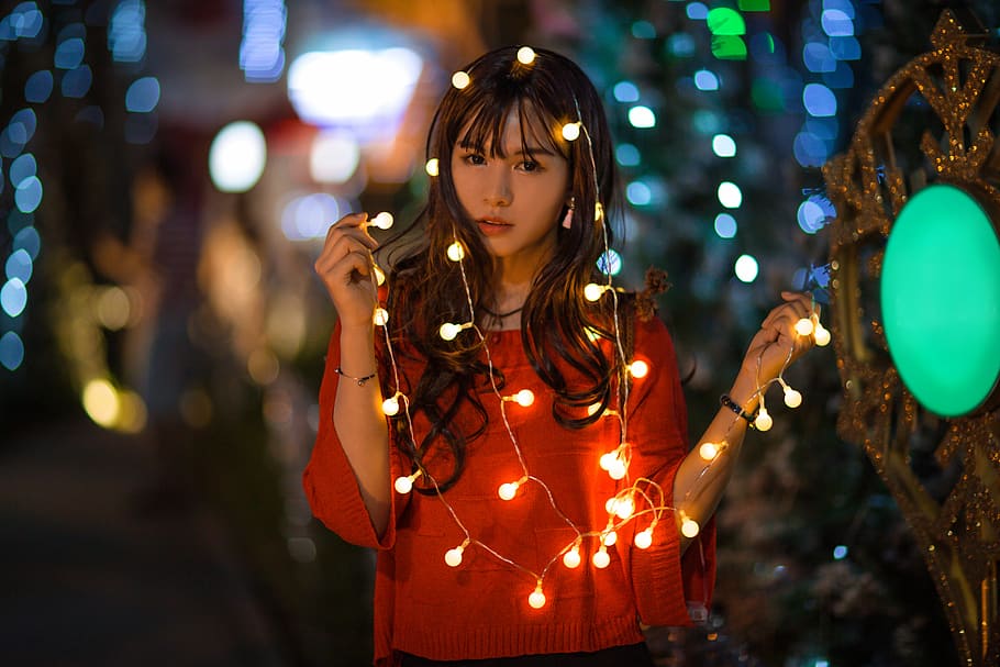 woman wearing red long-sleeved top holding string lights selective focus photography, HD wallpaper